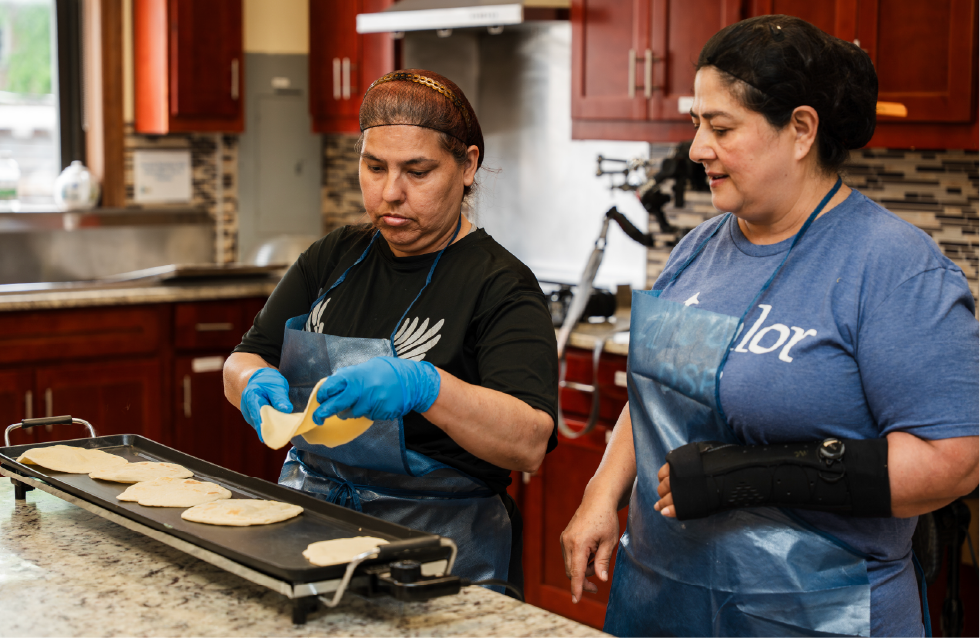 El valor staff assisting an adult woman to make tortillas