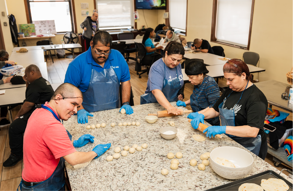 Adults making food at El Valor kitchen