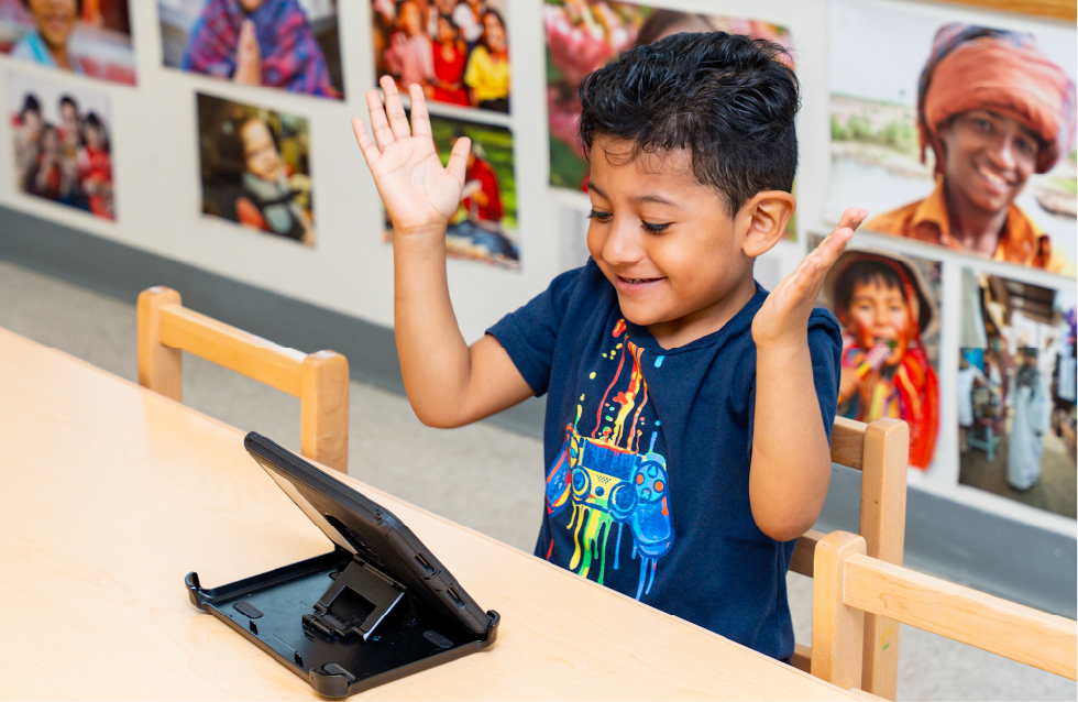 Little boy in El Valor classroom learning on a tablet