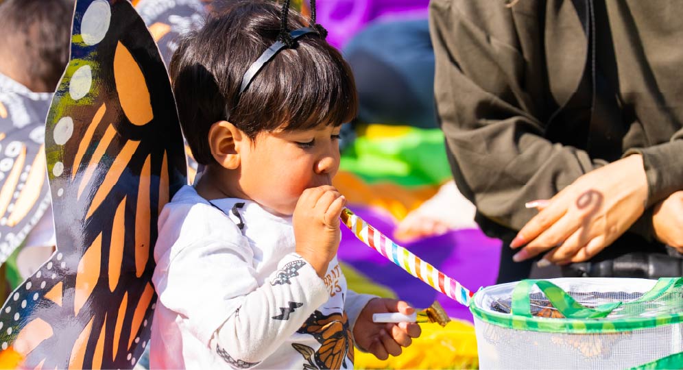 A young child explores colorful materials at a table.