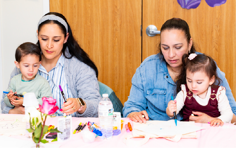 Mothers and children make crafts together at a table.