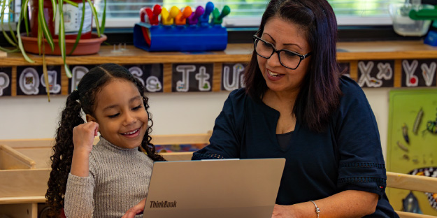 Child learning on a laptop with a guardian