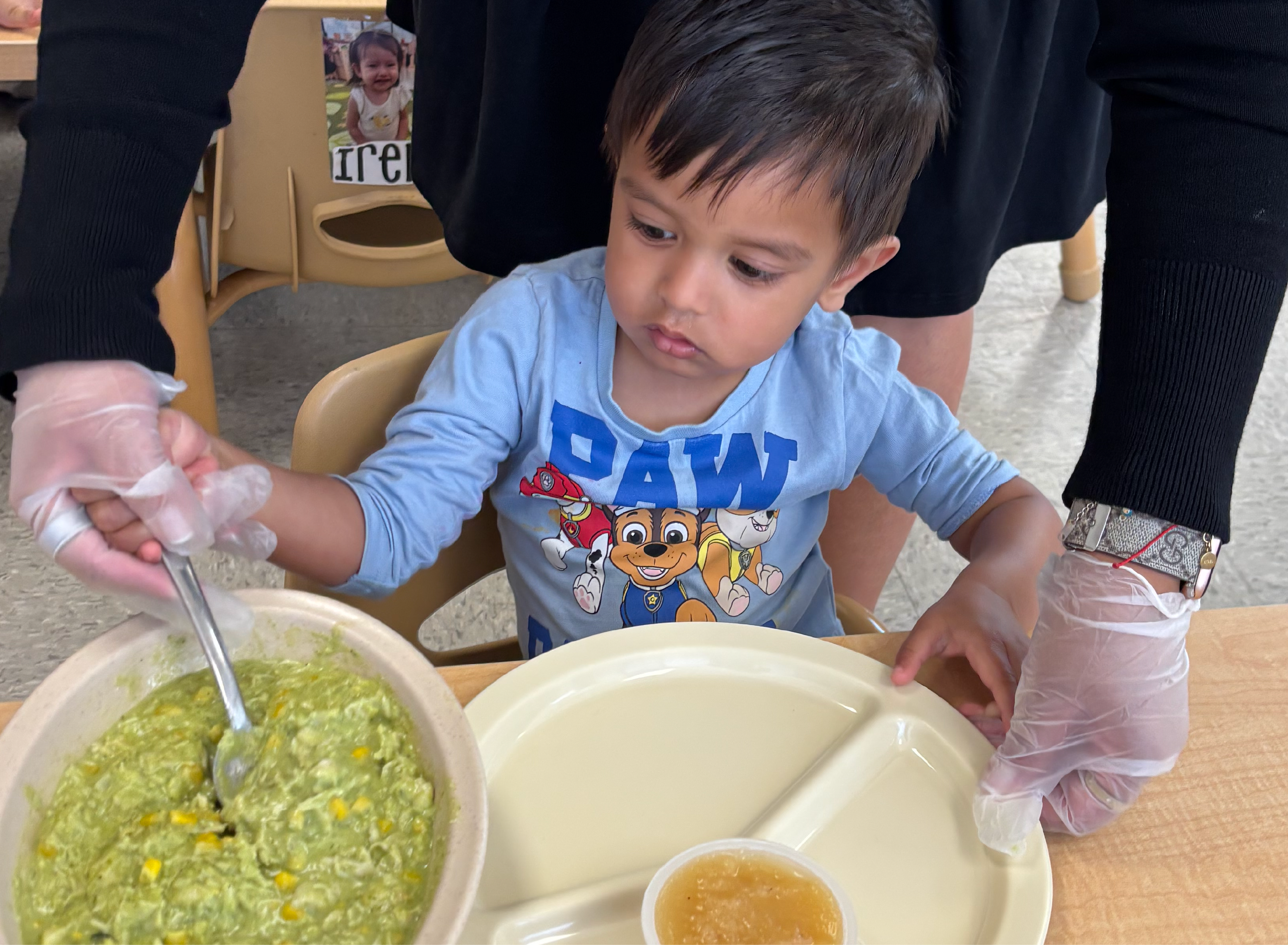 Hands prepare fresh greens in bowls during an El Valor cooking activity.